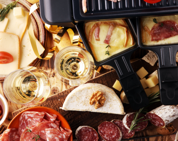 A hot raclette grill with its name-worthy raclette cheese is served with various types of meat, vegetables, and fresh bread.