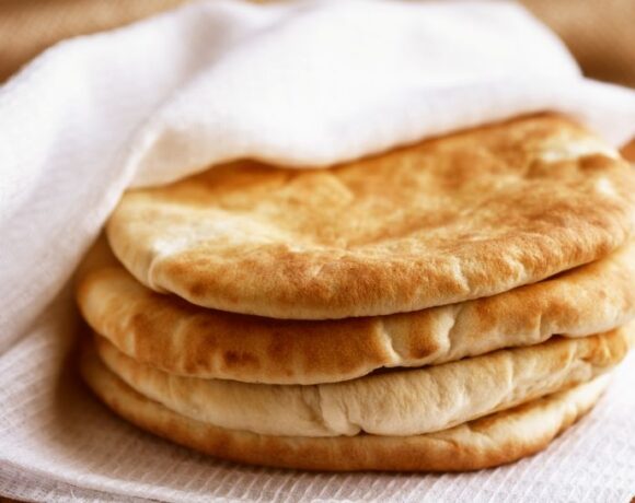 4 pita bread pockets stacked on top of each other and tucked into a white cloth napkin