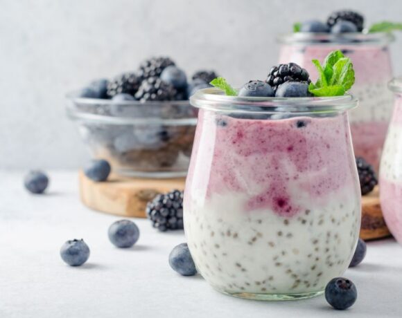 chia pudding with blueberries displayed in glass jars on white background.