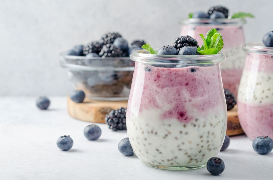 chia pudding with blueberries displayed in glass jars on white background.